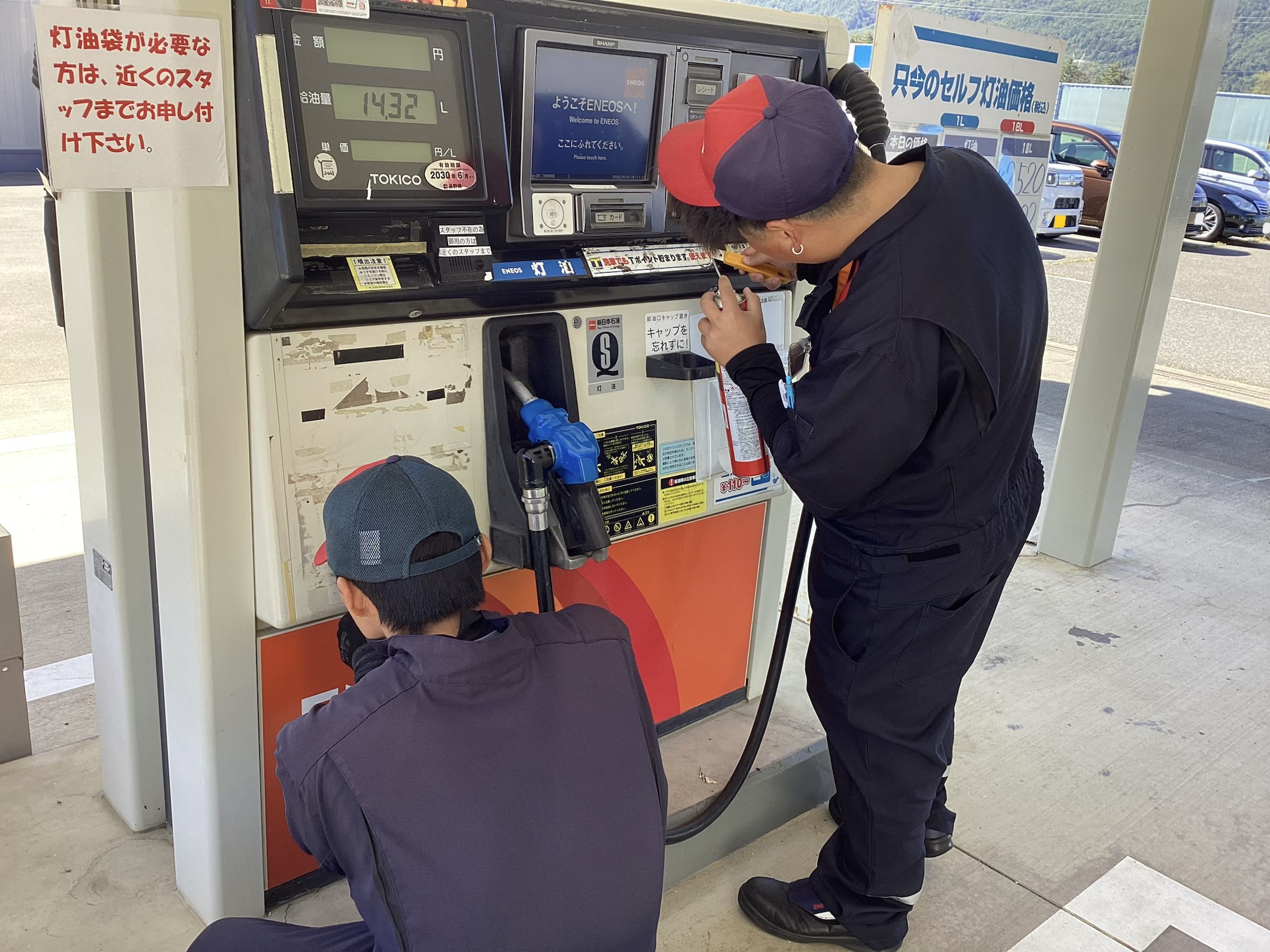 ルート19塩尻TSのスタッフが灯油の軽量機のシール剥がしと清掃を行う様子