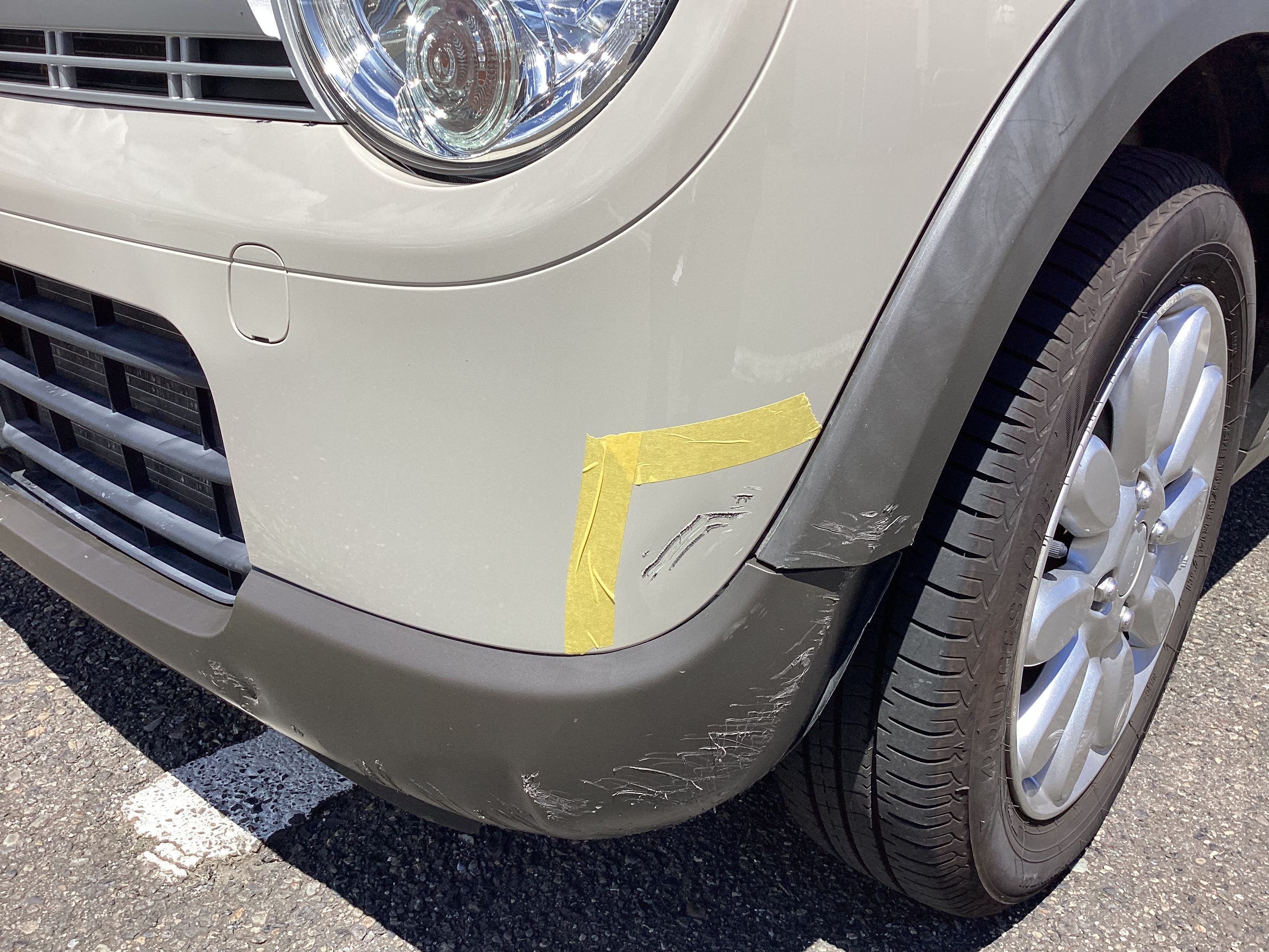 ベージュのスズキ　アルトラパンのフロントバンパーと樹脂バンパーにエグレキズがある施工前の状態