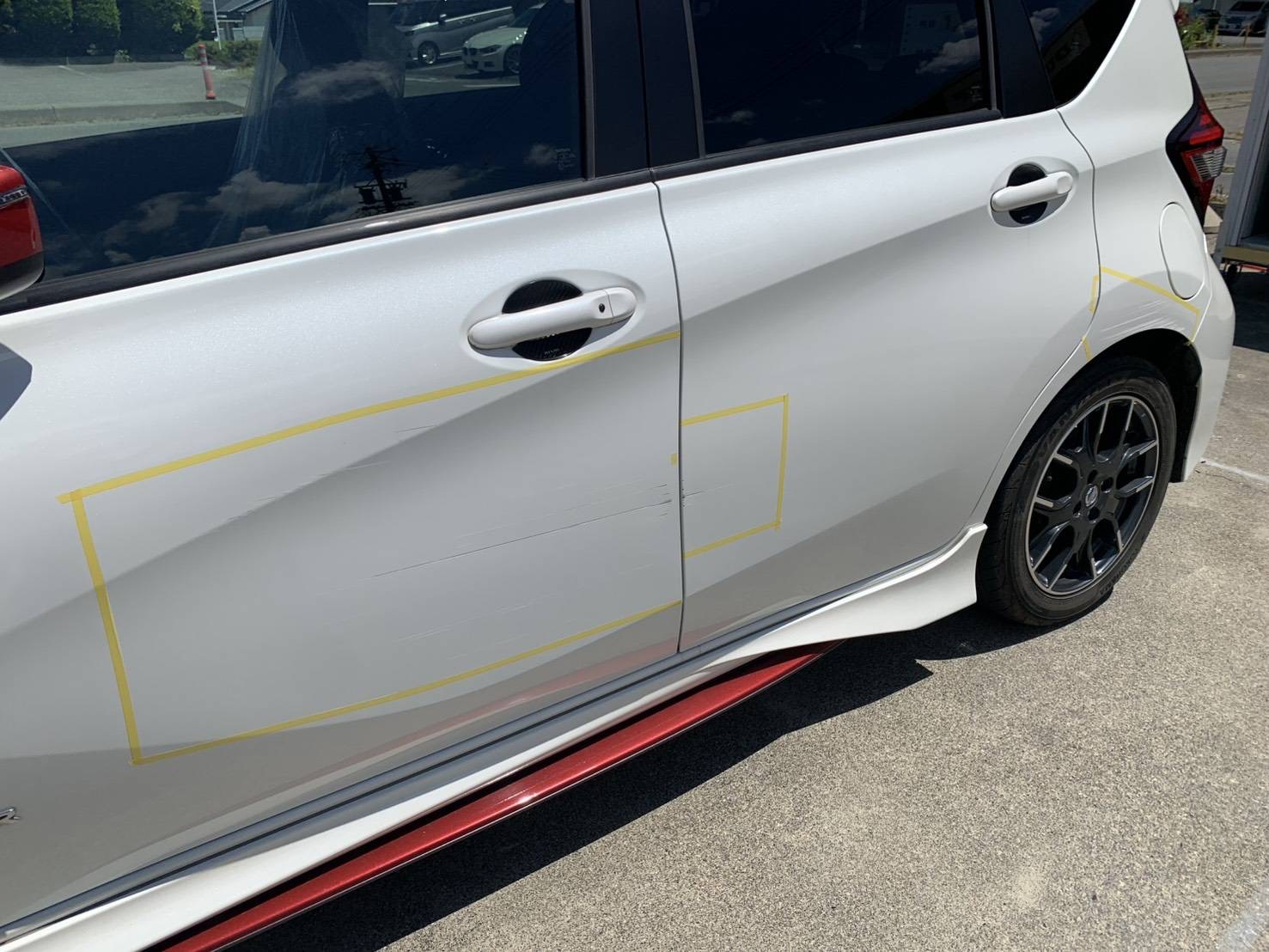 白い日産　ノートNISMOの左ドア〜左リアクォーターに線キズがある施工前の状態