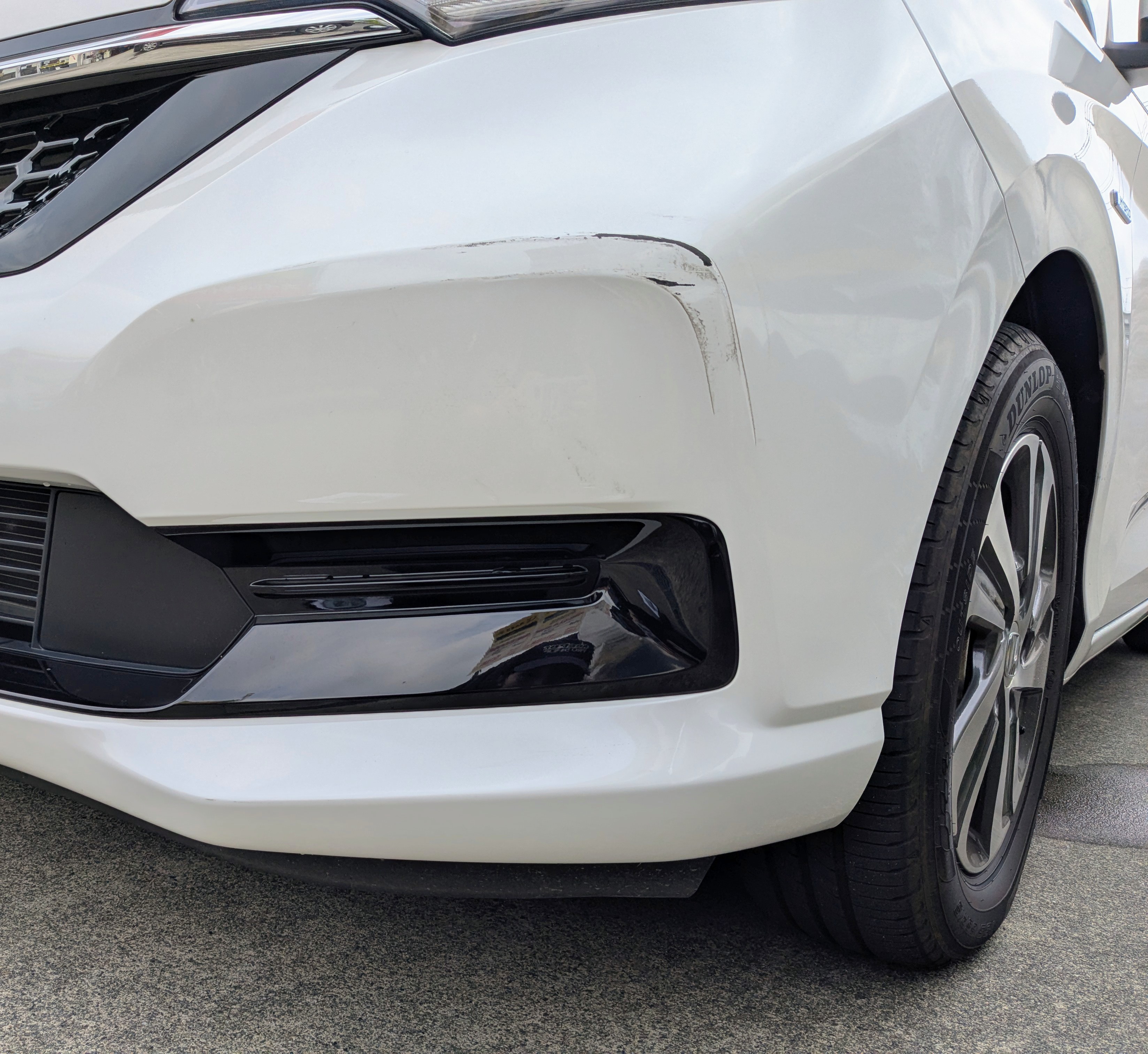 白いホンダ　フリードのフロントバンパー左側にえぐれキズがある施工前の状態