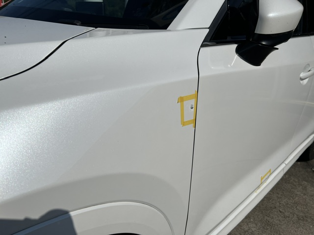 白いマツダ／CX-5び左側フロントフェンダーのへこみ傷を修理した施工前